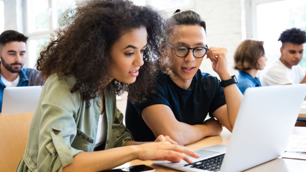 Two students looking at a laptop screen