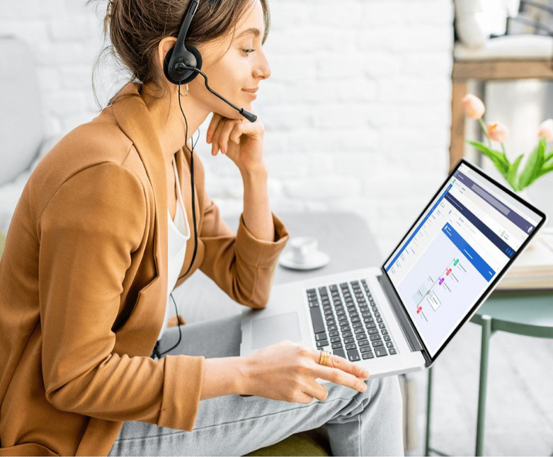 Customer service representative chatting to a customer through a headset, while looking at data on a laptop